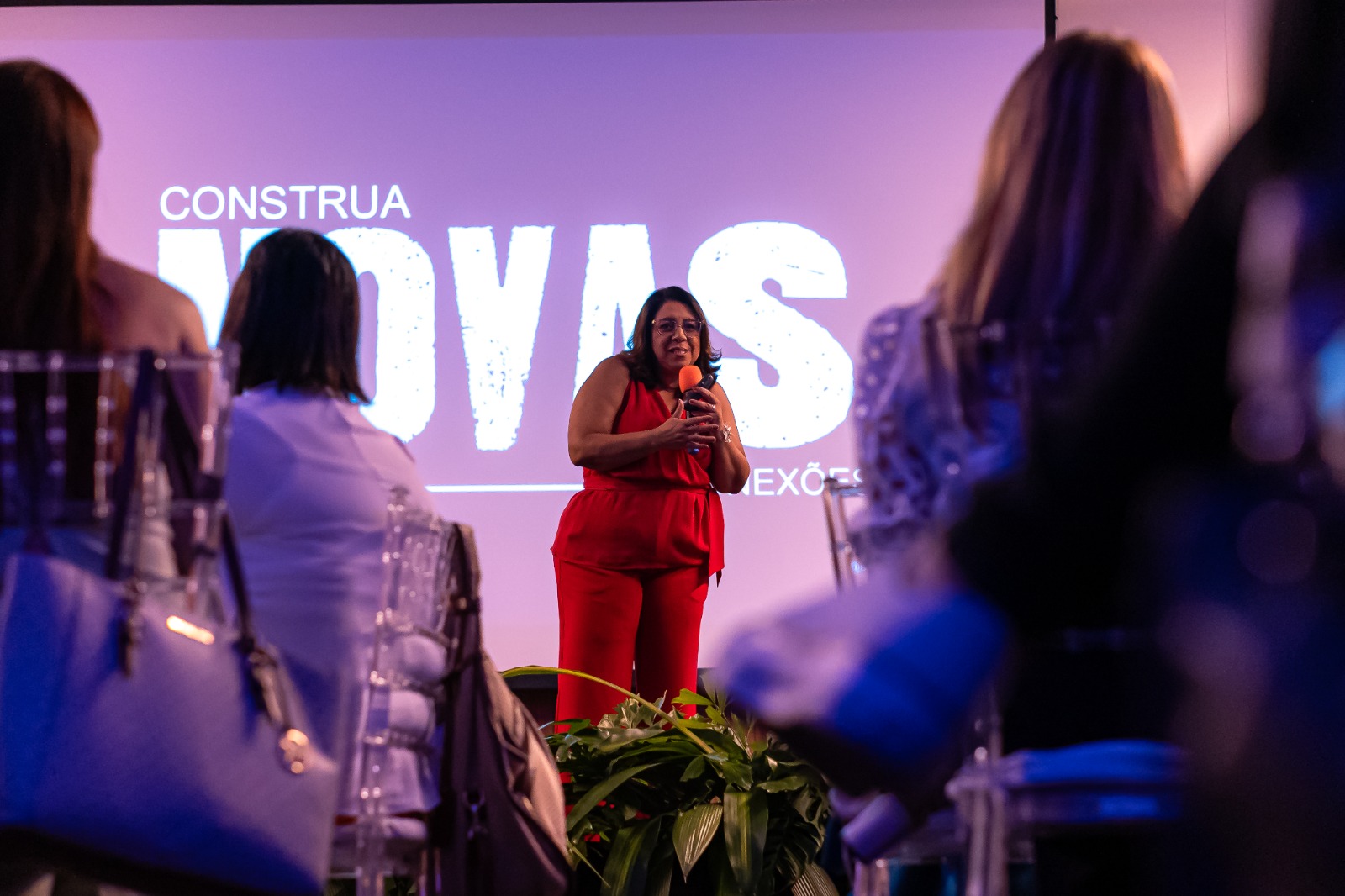 Andréa Rodrigues de vermelho, com microfone, durante uma apresentação em edição anterior