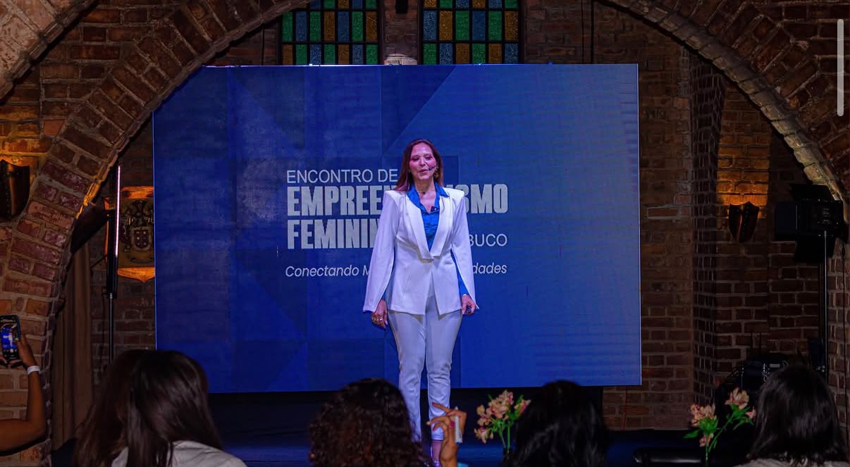 Palestra no palco com painel do encontro ao fundo
